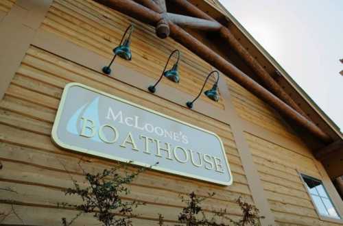 Sign for McLoone's Boathouse on a wooden building, featuring outdoor lighting fixtures.