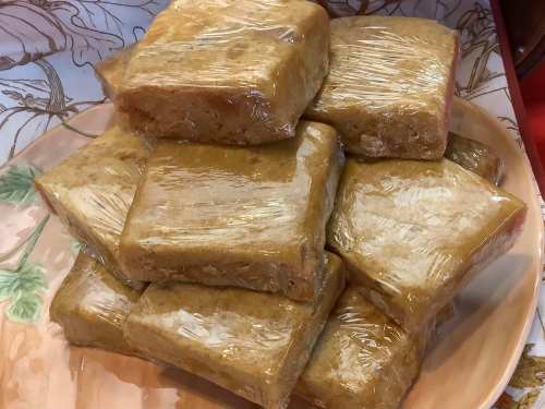 A stack of wrapped, rectangular rice cakes on a decorative plate.