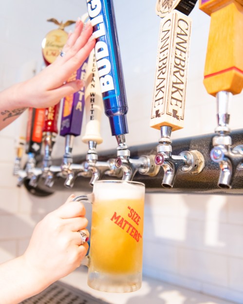 A hand pours beer from a tap into a frosted mug with "SIE MATTERS" printed on it, surrounded by various beer taps.