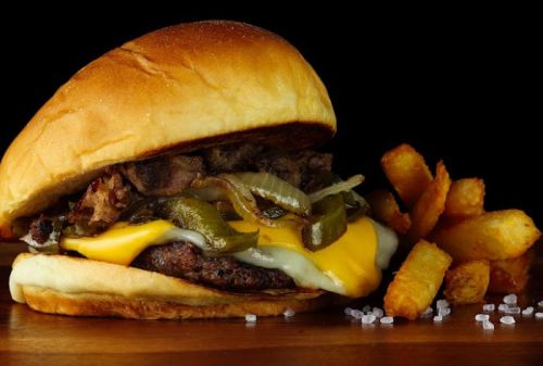 A juicy cheeseburger with grilled onions and jalapeños, served with crispy fries on the side.