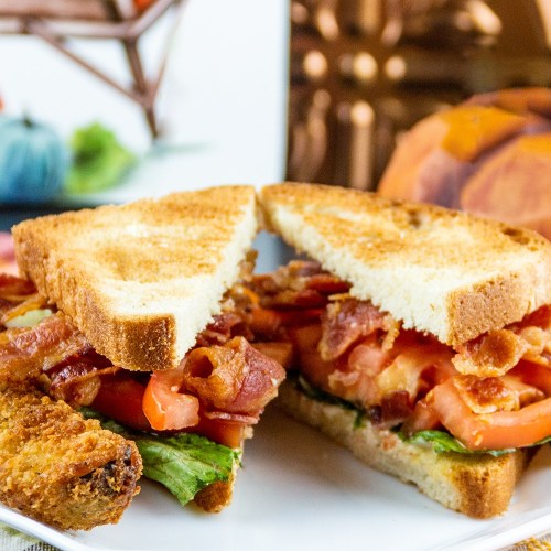 A close-up of a sandwich with bacon, lettuce, and tomato, served on toasted bread.
