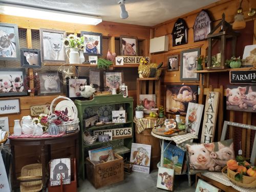 A cozy farm-themed display with vintage decor, signs, and farm animal artwork, featuring fresh eggs and rustic items.