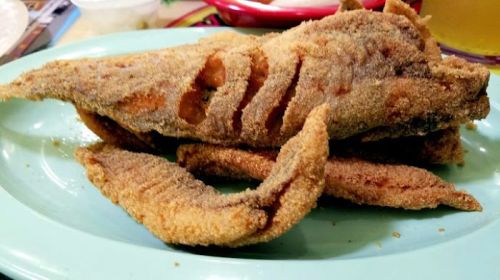A plate of crispy fried fish, featuring a golden-brown coating and a side of fried fish pieces.