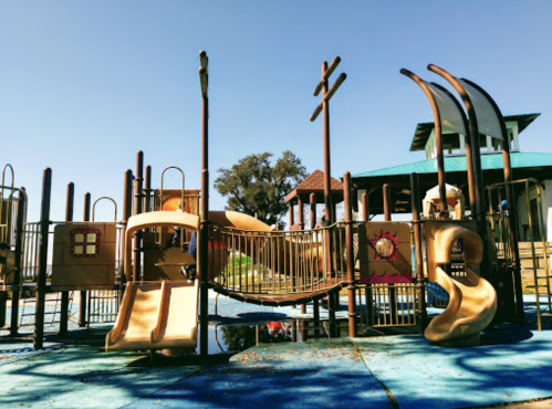 Colorful playground equipment with slides and climbing structures under a clear blue sky.