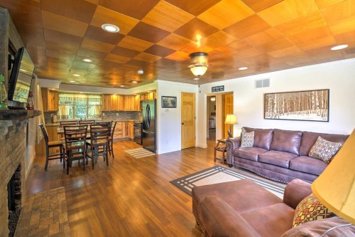Cozy living room with a brown sofa, wooden ceiling, and open kitchen area featuring a dining table and modern appliances.