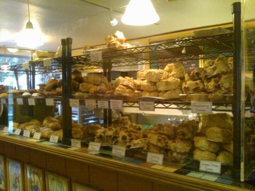 A display case filled with various baked goods, including scones and pastries, arranged on wire shelves.