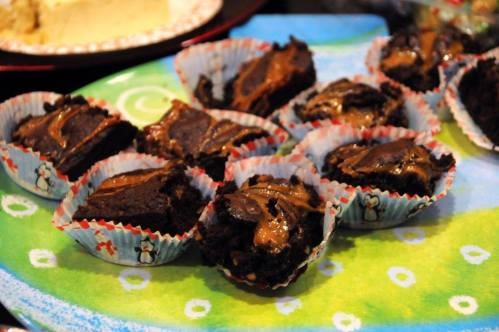 A colorful plate with chocolate brownies topped with caramel, arranged in festive cupcake liners.