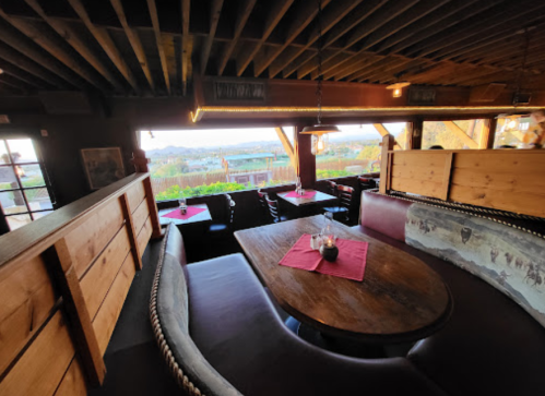 Cozy restaurant interior with wooden decor, a large table, and scenic views through windows.