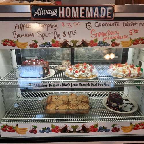 Display case filled with homemade desserts, including banana split pie, chocolate cream cake, and strawberry millennaire.