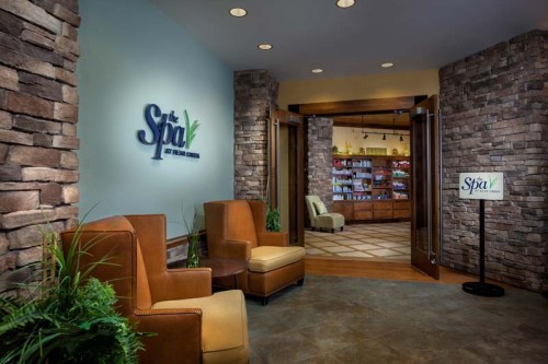 Welcoming spa entrance with stone walls, cozy seating, and a display of spa products in the background.