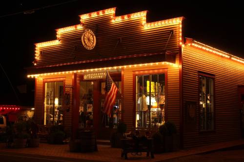 A brightly lit storefront at night, adorned with string lights and an American flag, creating a warm, inviting atmosphere.