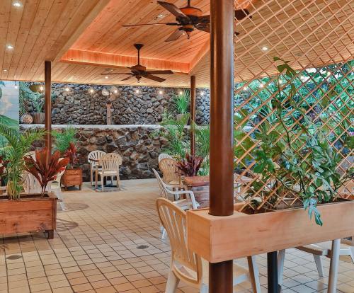 A cozy outdoor dining area with wooden seating, plants, and a stone wall backdrop under a wooden roof.