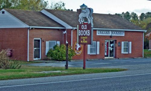A brick building with a sign for "Unicorn Bookshop," featuring "Old Books" and "Used & Rare" on the storefront.