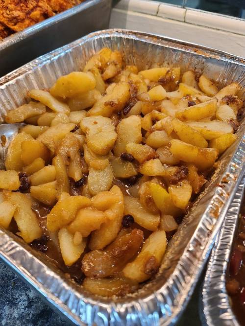 A tray of cooked apple slices with a caramelized glaze, featuring a mix of yellow and brown apples.