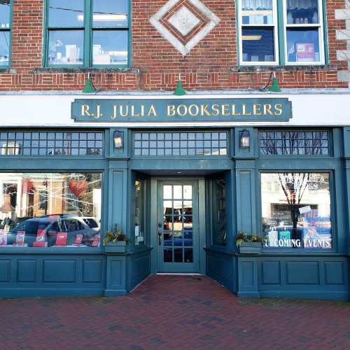 Exterior of R.J. Julia Booksellers, featuring a green facade and large windows displaying books and event information.