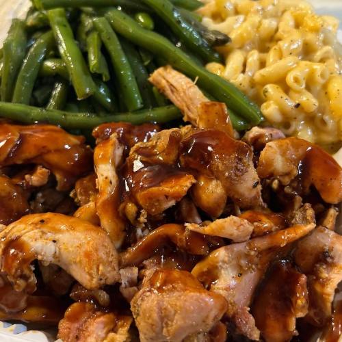 A plate featuring barbecue chicken, green beans, and macaroni and cheese.