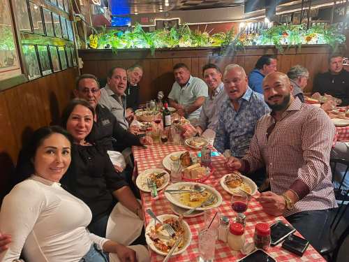 A group of people enjoying a meal together at a restaurant, seated around a table with checkered tablecloths.
