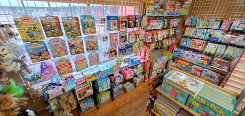 A colorful display of toys and craft kits on shelves, with plush animals and various children's items in a store.