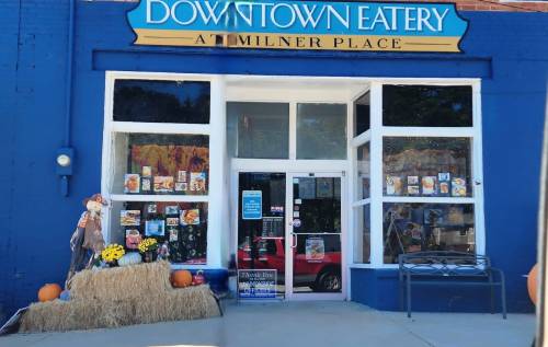A blue storefront with "Downtown Eatery" sign, featuring fall decorations, pumpkins, and hay bales outside.