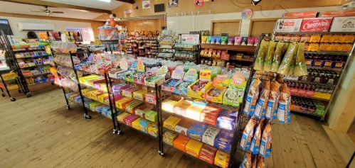 A colorful display of various candies and snacks on shelves in a well-lit store interior.