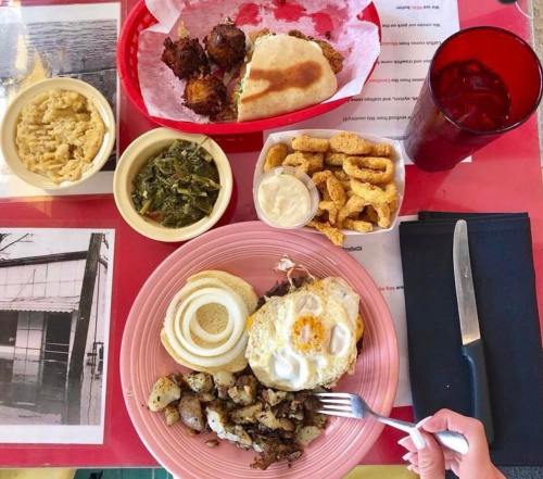 A colorful spread of Southern comfort food, including fried chicken, greens, potatoes, and a drink on a red table.