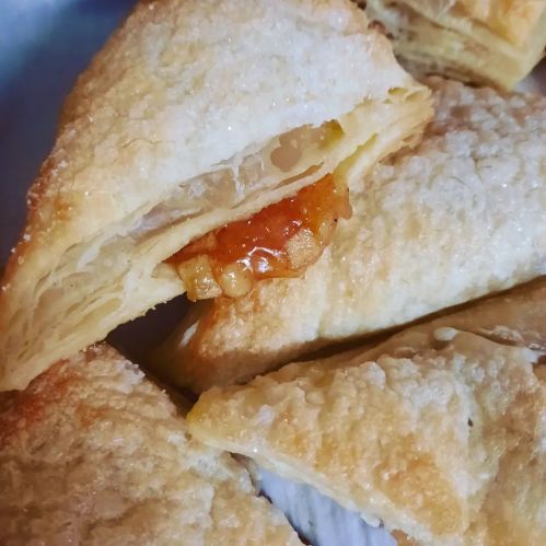 Close-up of flaky pastry with a golden filling, showcasing layers and a shiny glaze.