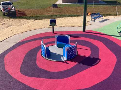 A colorful playground with a circular spinning structure on a vibrant, patterned surface.