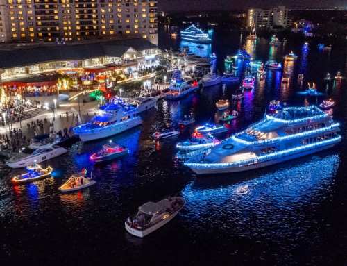 Aerial view of a festive harbor at night, filled with brightly lit boats and a lively waterfront scene.