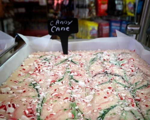 A tray of peppermint candy cane fudge with a black sign labeled "Candy Cane" on top.