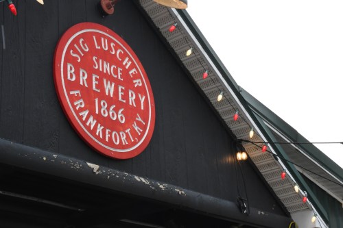 Sign for Sig Luscher Brewery, established 1866, located in Frankfort, NY, displayed on a dark building with lights.