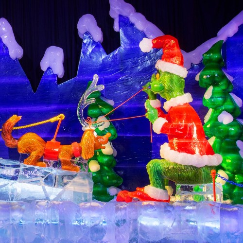 Colorful ice sculpture featuring the Grinch, his dog, and festive trees in a winter scene.