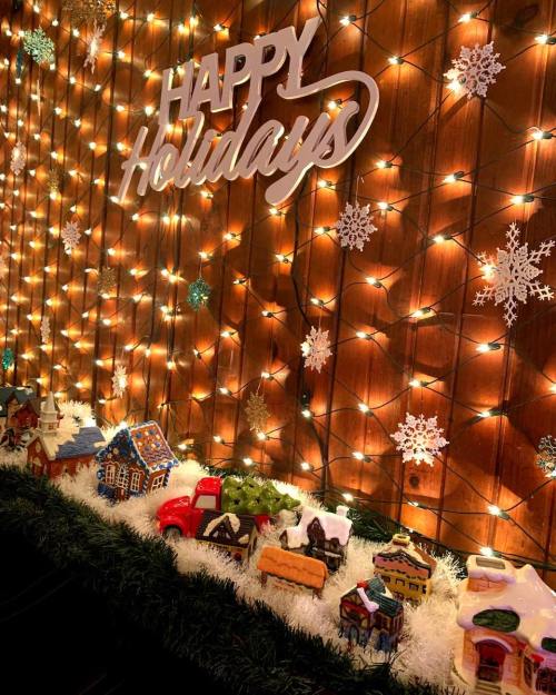 A festive display with "Happy Holidays" sign, twinkling lights, snowflakes, and colorful gingerbread houses.