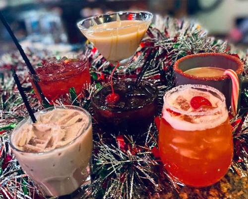 A festive display of colorful cocktails surrounded by shiny holiday decorations.