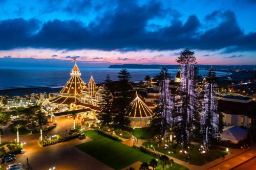A beautifully lit resort at dusk, with ocean views and decorative trees, creating a serene and inviting atmosphere.