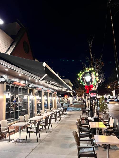 Outdoor dining area of a restaurant at night, decorated with festive lights and holiday decor.