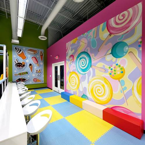 Brightly colored interior of a candy-themed space with playful wall murals and a vibrant floor.