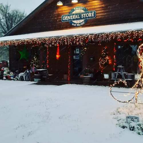 A cozy general store decorated with colorful lights, surrounded by snow and festive decorations.