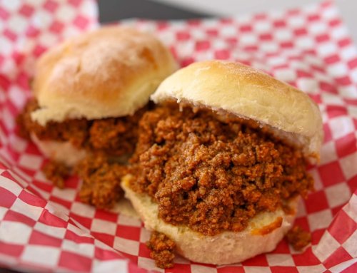 Two sliders filled with a savory meat mixture, served in a red and white checkered basket.