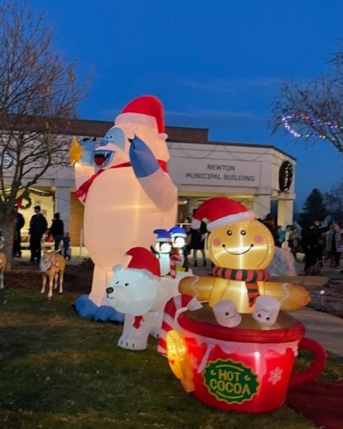 Inflatable holiday decorations outside the Newton Municipal Building, featuring a yeti, polar bear, and a cocoa cup.