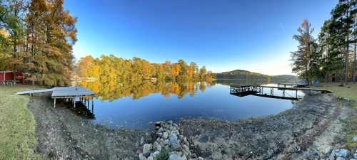 A serene lake at sunrise, surrounded by colorful autumn trees and wooden docks reflecting on the calm water.