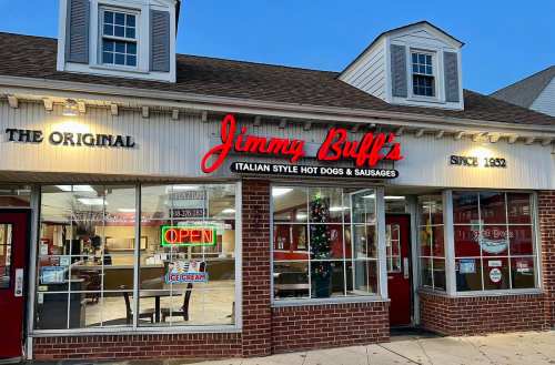 Exterior of Jimmy Buff's restaurant, featuring a bright sign and open window, with festive decorations visible inside.