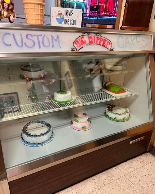 Display case with various custom cakes, featuring colorful decorations and different designs.