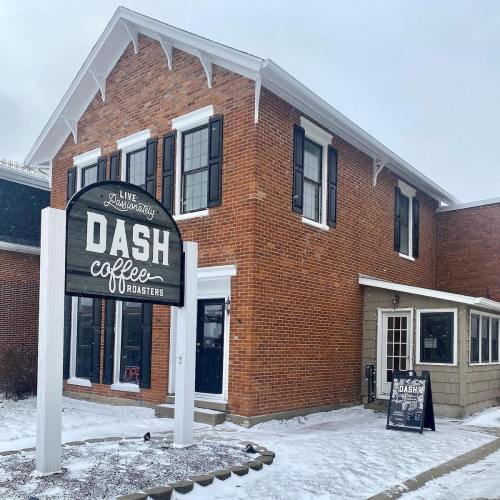 Exterior of Dash Coffee Roasters, a brick building with large windows and a sign, surrounded by snow.