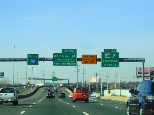 Highway exit signs for Fairfield Metro and RR Station, with vehicles traveling on a clear day.