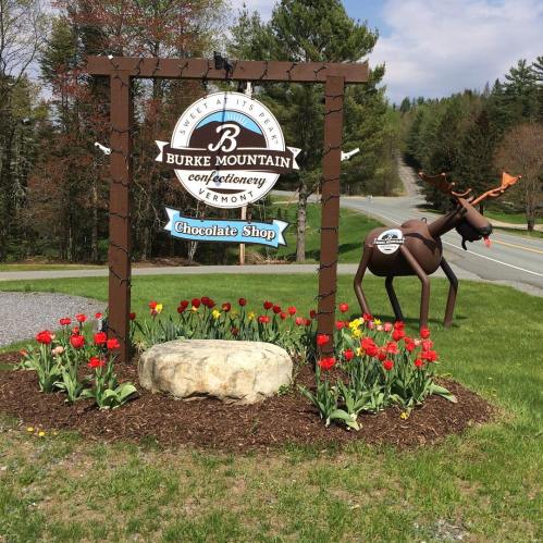 Sign for Burke Mountain Confectionery in Vermont, featuring a chocolate shop and surrounded by colorful tulips.