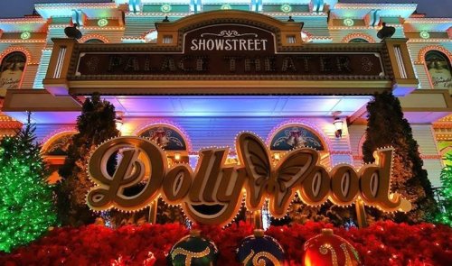 Colorful lights adorn the Dollywood entrance, featuring festive decorations and a vibrant sign in front of the Palace Theater.