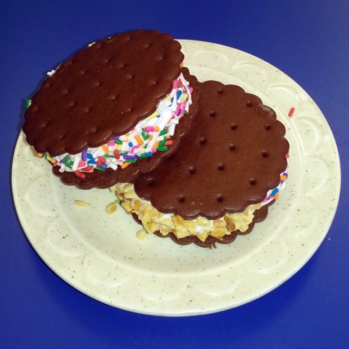 Two ice cream sandwiches with colorful sprinkles on a white plate, set against a blue background.