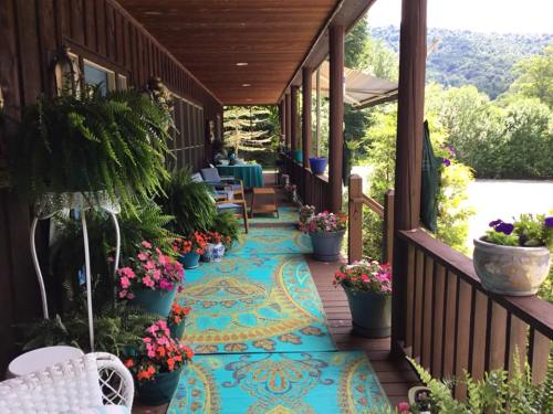A cozy porch with colorful rugs, potted plants, and a scenic view of greenery and mountains in the background.