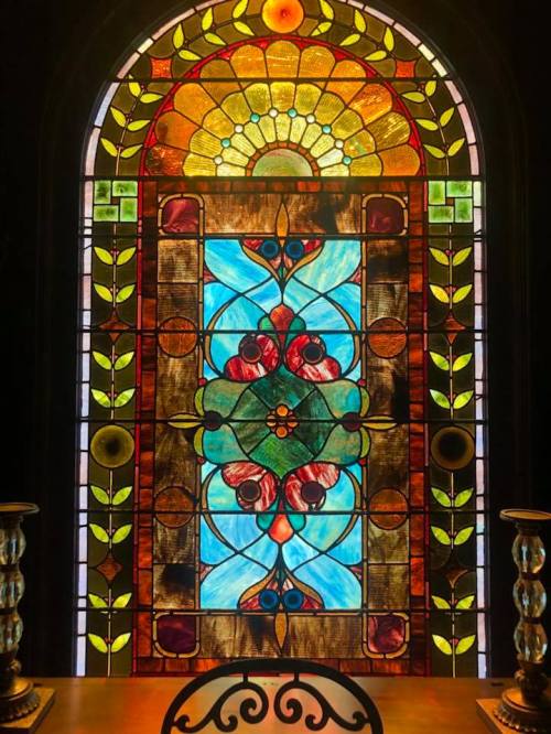 Colorful stained glass window featuring floral and geometric patterns in vibrant hues.