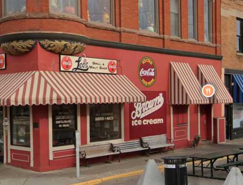 A red brick building with striped awnings, featuring a sign for "Bram's Ice Cream" and a grill and malt shop.